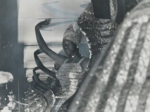 Black and white photograph of dance group Les Ballet Africains posing in front of a mirror.